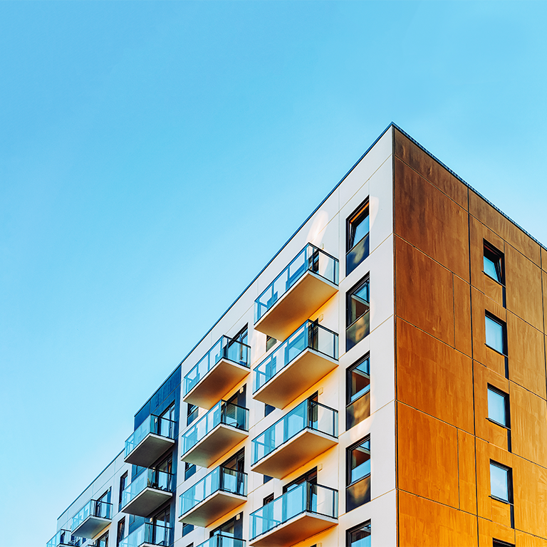  Modern multi-story residential building with balconies under clear blue sky.