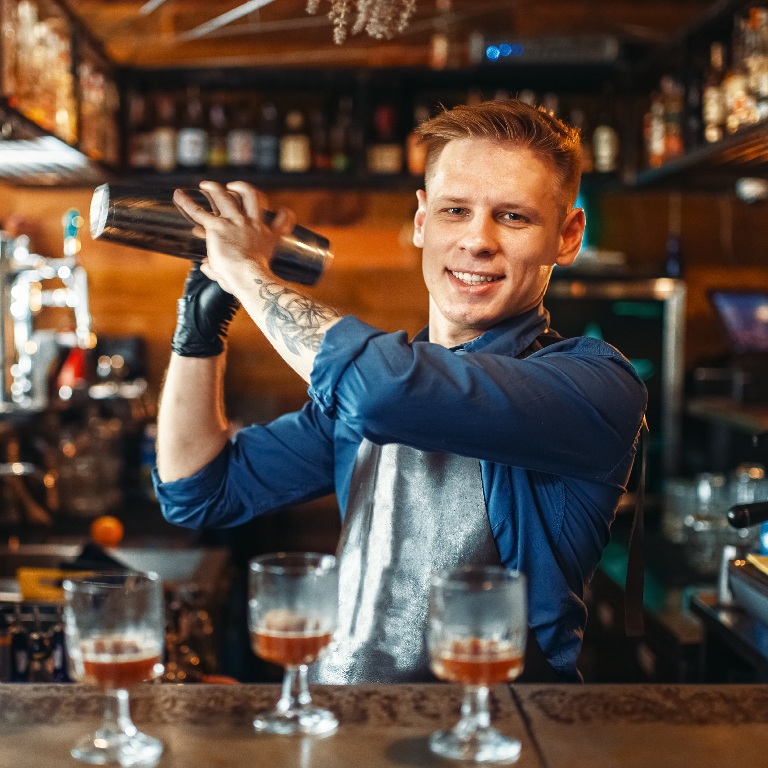 Bartender shaking a drink behind the bar in a leased pub, illustrating what insurance does a leased pub operator need.