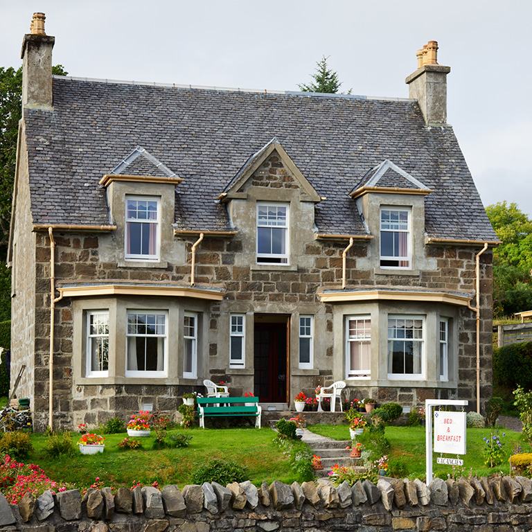 Guesthouse liability review showing a stone guesthouse with a garden and a bed and breakfast sign outside.