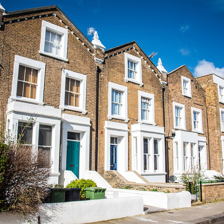 Row of brick townhouses with white trim and front doors, showing a guesthouse insurance property for B&B owners.
